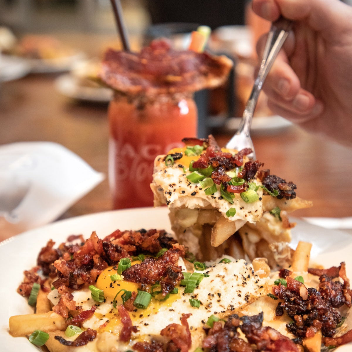 Plate of loaded fries with a fork, napkin, and bottle in the background