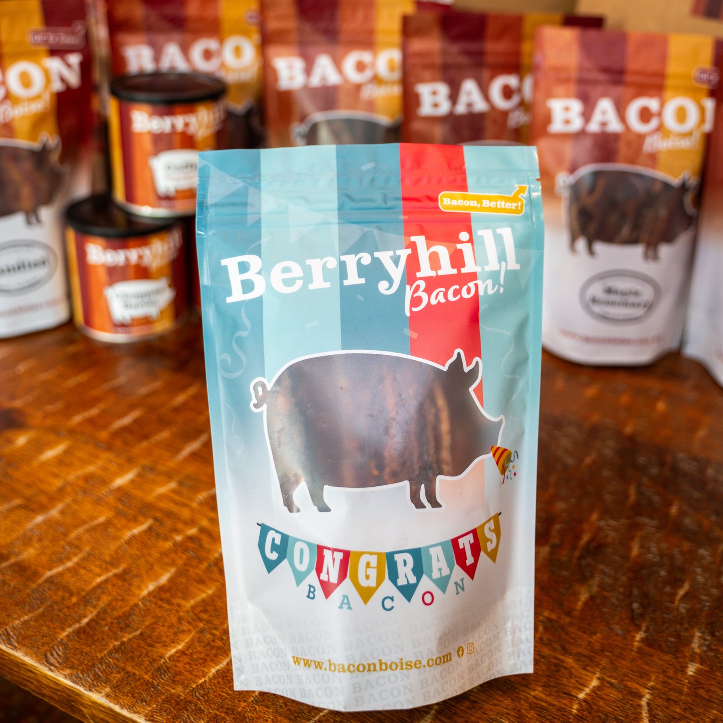 A package of Berryhill Bacon with a graphic of a pig and the text 'CONGRATS BACON'. Other packages of bacon are visible in the background.