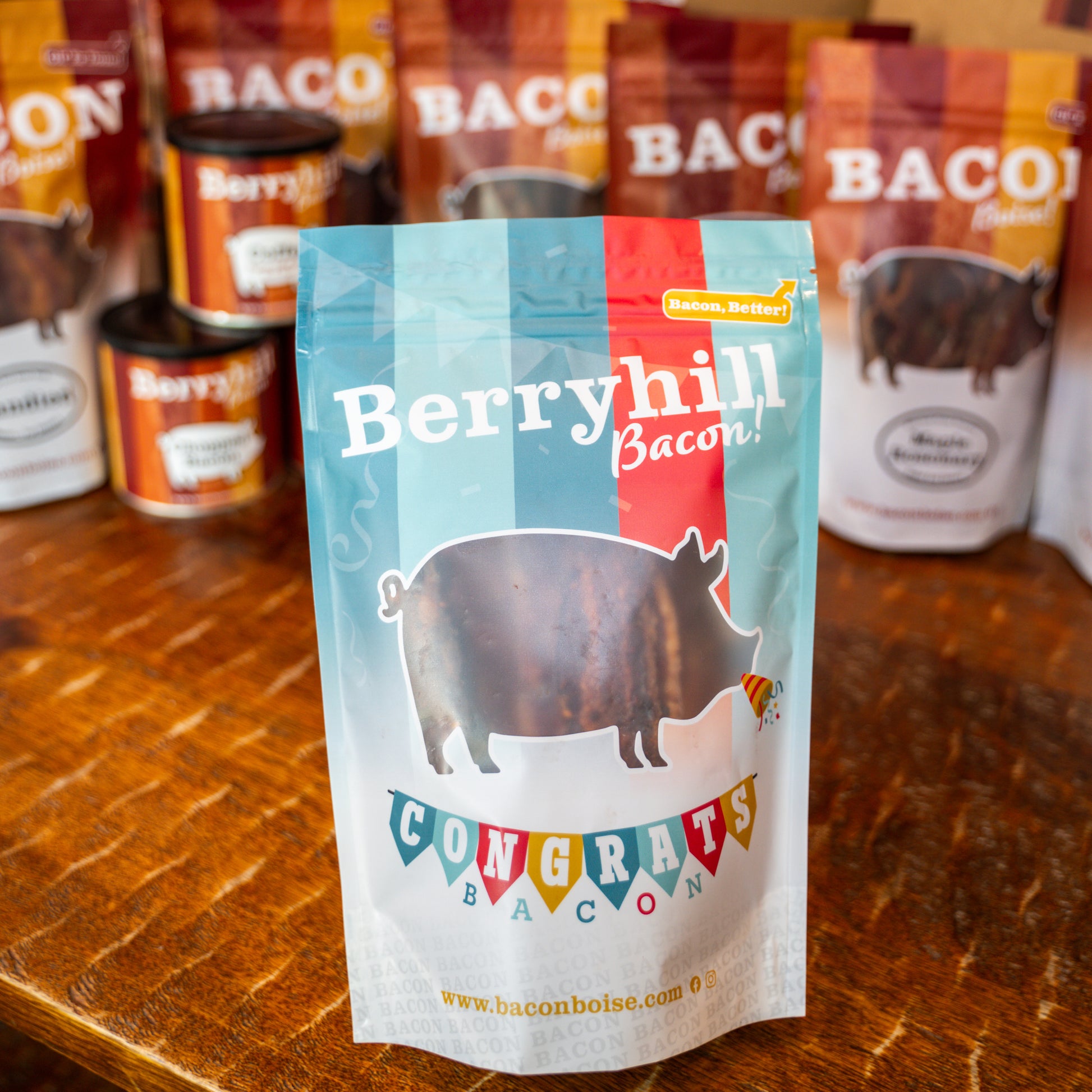 A package of Berryhill Bacon with a graphic of a pig and the text 'CONGRATS BACON'. Other packages of bacon are visible in the background.