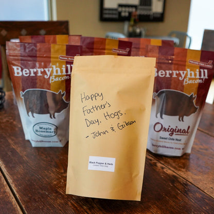 Bags of berryhill bacon on a wooden table with a personalized card.