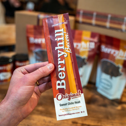 Hand holding a Berryhill Bacon package with a blurred store shelf in the background