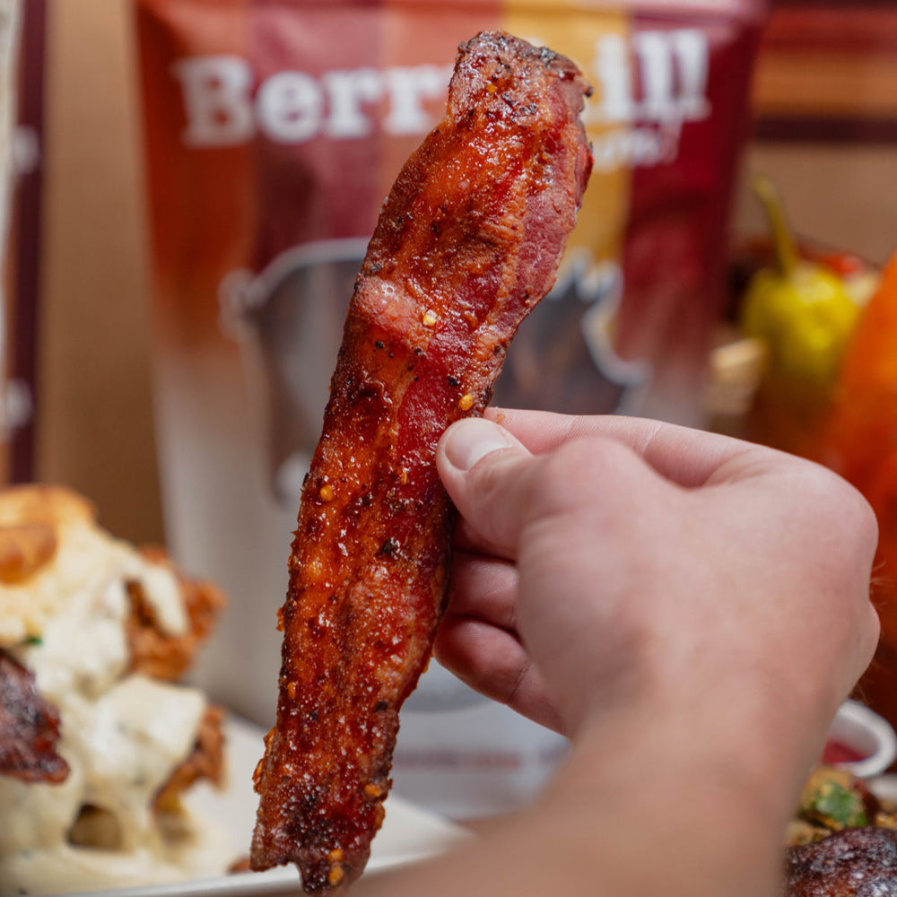 Hand holding bacon with 'Berryhill' packaging in the background