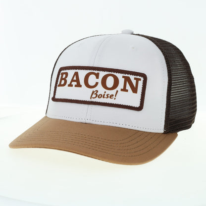A tan trucker hat with BACON Boise logo on the front. 